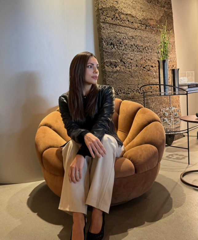 Arquiteta Ana Weber sentada em uma poltrona de veludo caramelo