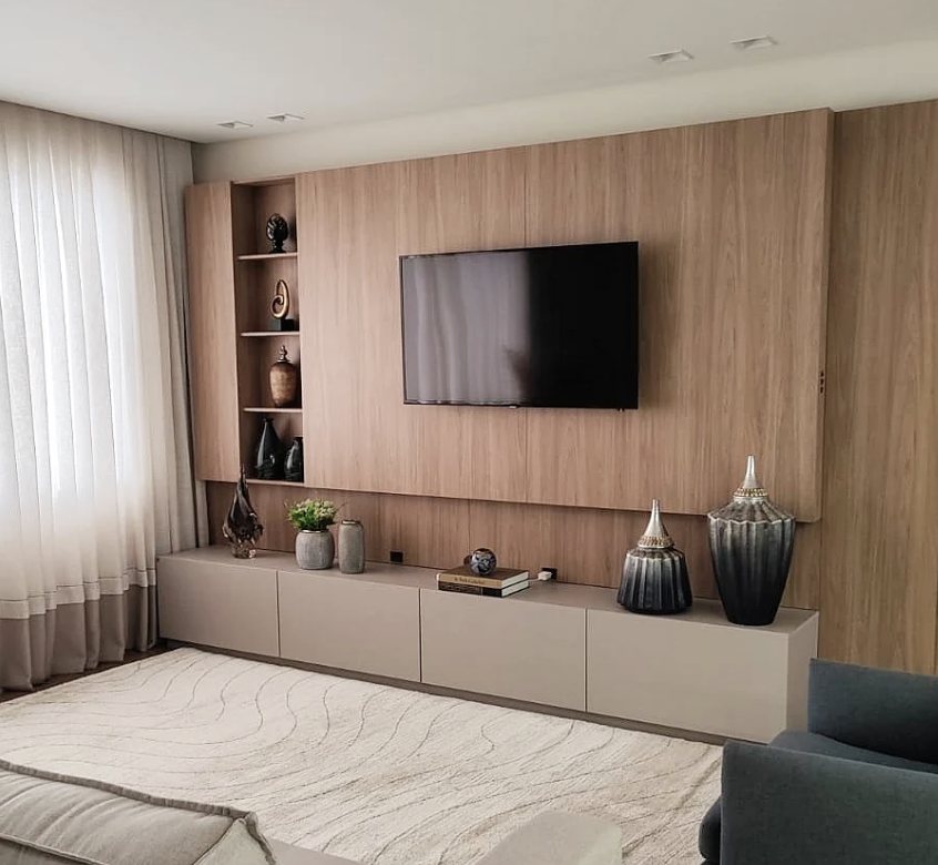 Sala de estar com painel amadeirado e rack em tom neutro